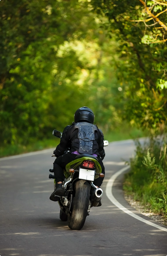 Motorbike rider on a winding forest road