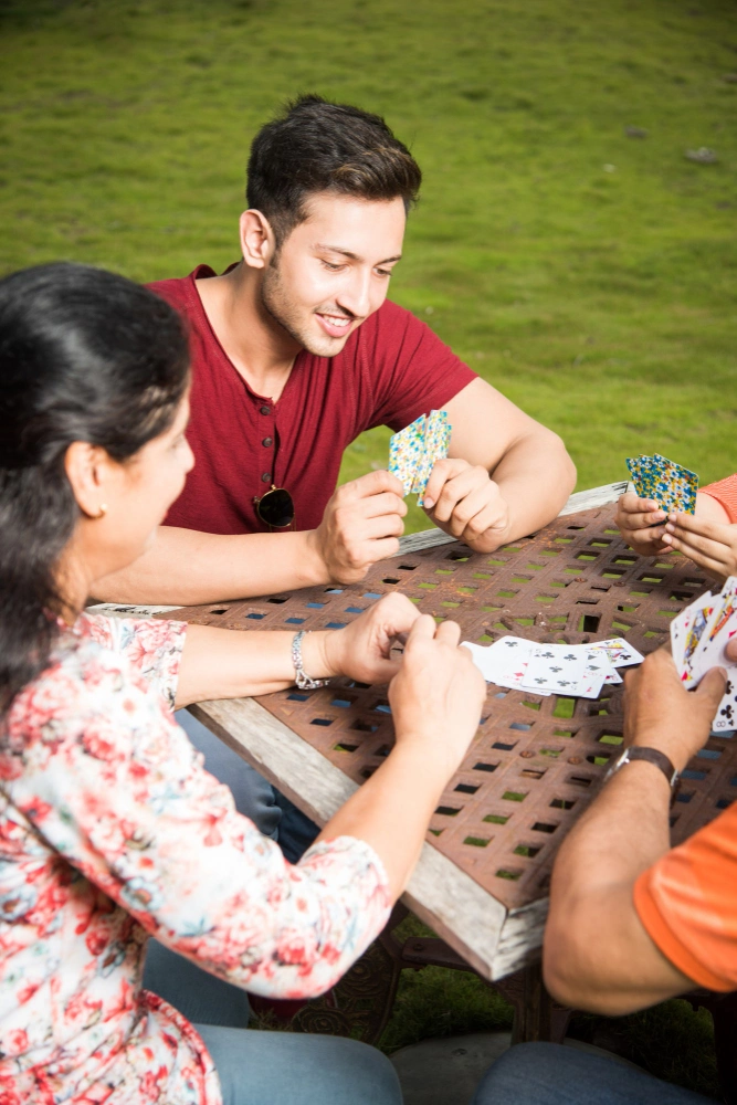 Family playing cards at a table on the lawn