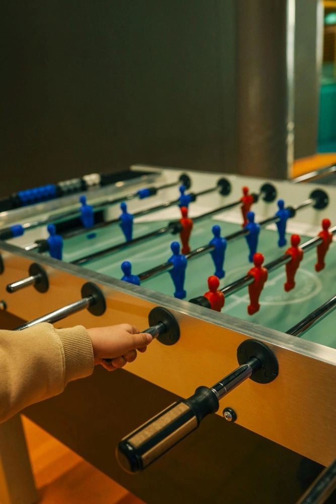 Hand on a foosball table handle mid-game